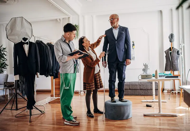 A Man and Woman Take Measurements of a Customer highlighting Custom Men's Suits in Chicago, IL