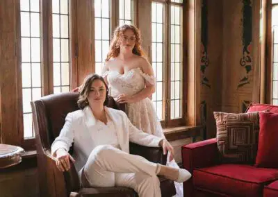 Two women dressed in white seated on a couch in a tailor's studio in Chicago, IL