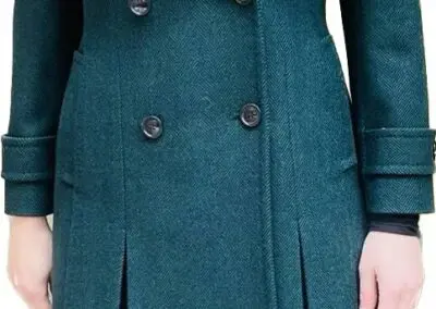 A woman in a green coat and black pants stands confidently in Chicago, IL